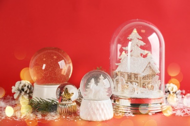 Image of Beautiful Christmas snow globes on red background, bokeh effect