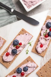 Photo of Tasty cracker sandwiches with cream cheese, blueberries, red currants and thyme on table, flat lay