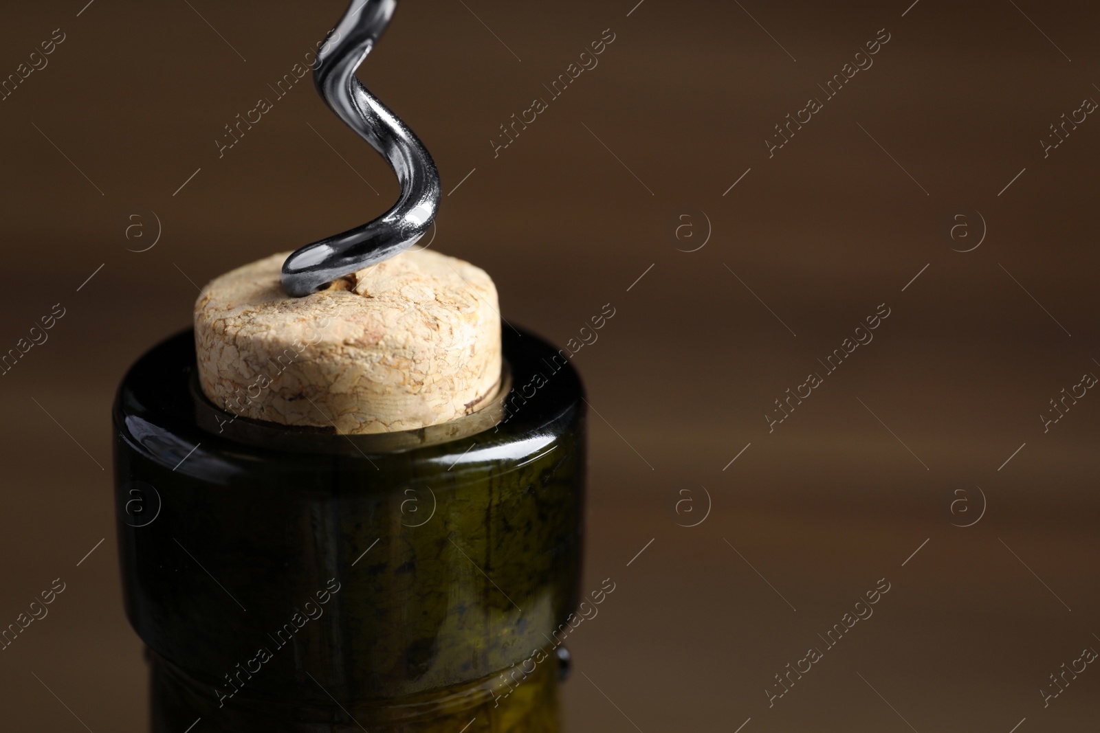 Photo of Opening wine bottle with corkscrew on color background, closeup. Space for text