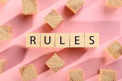 Photo of Word Rules made of wooden cubes with letters on pink background, flat lay