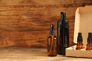 Photo of Bottles with oil in box on wooden table, space for text. Natural cosmetics