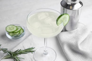 Glass of cucumber martini and ingredients on grey table
