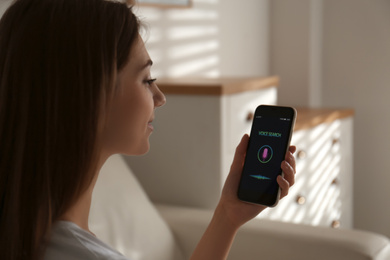 Photo of Woman using voice search on smartphone indoors