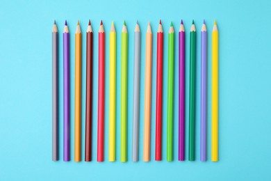 Colorful wooden pencils on light blue background, flat lay