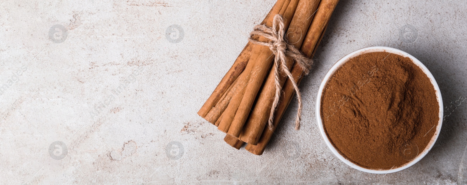 Image of Aromatic cinnamon sticks and powder on light table, flat lay with space for text. Banner design
