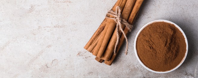 Aromatic cinnamon sticks and powder on light table, flat lay with space for text. Banner design