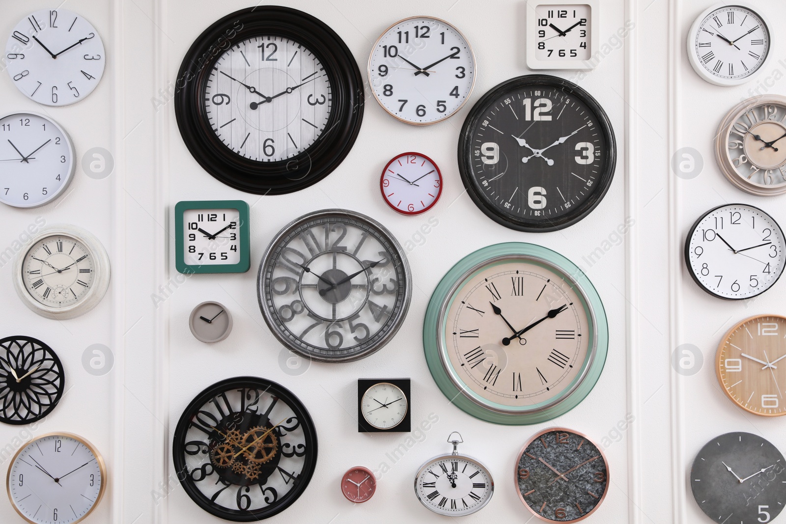 Photo of Collection of different clocks hanging on white wall