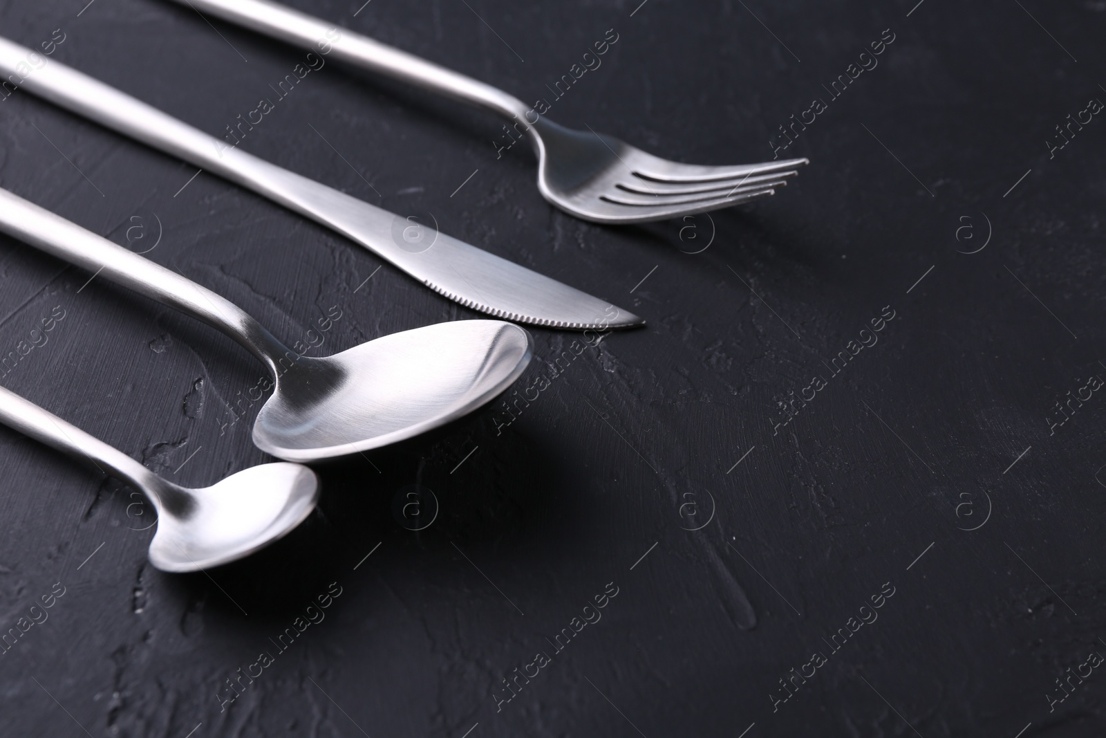 Photo of Beautiful cutlery set on black table, closeup