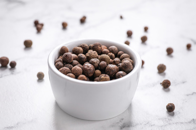Photo of Black peppercorns in bowl on white marble table