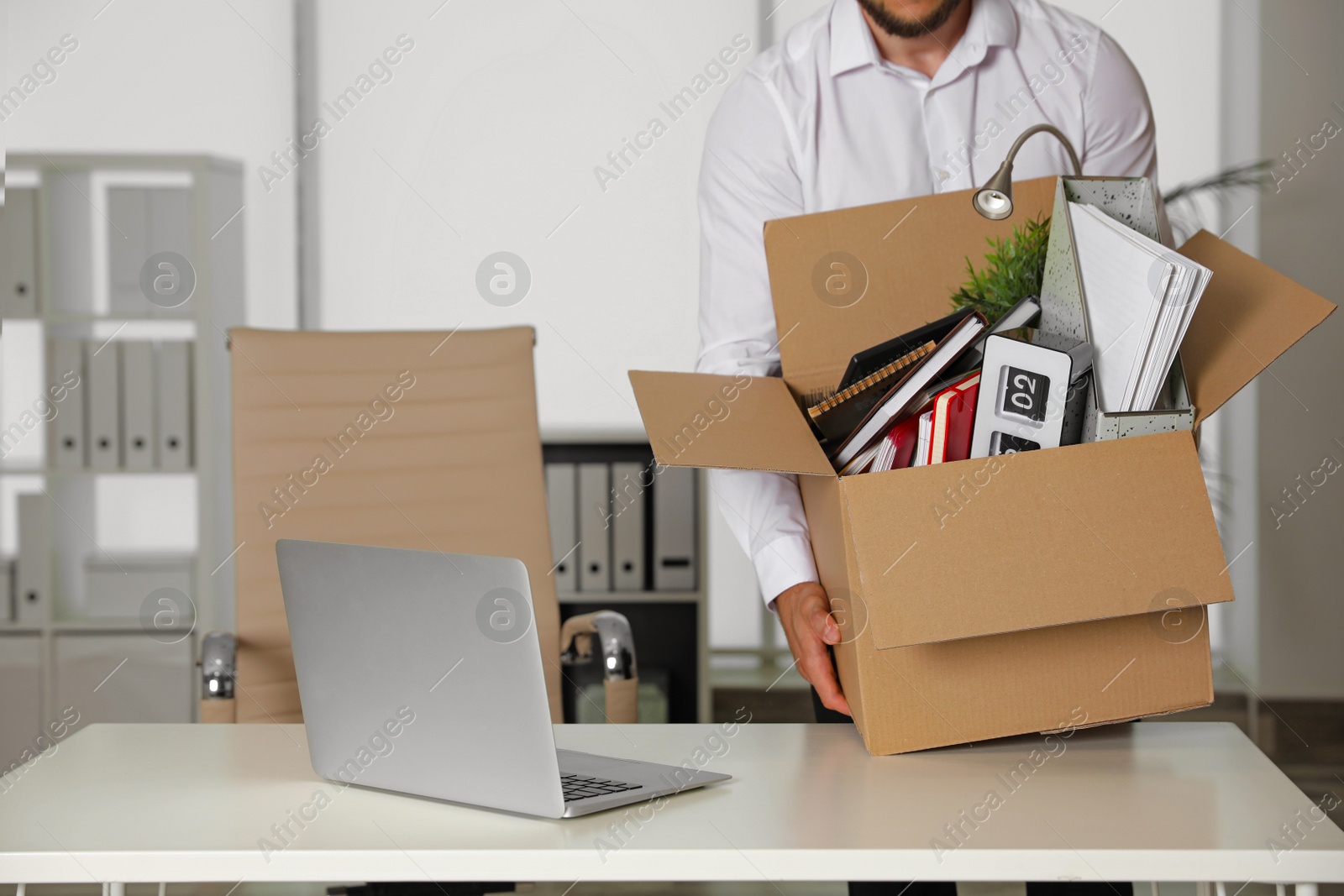 Photo of Young man with box of stuff in office, closeup