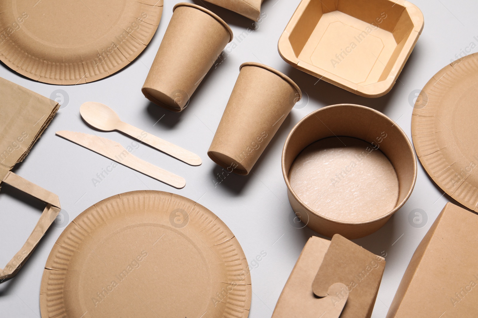 Photo of Eco friendly food packaging. Paper containers and tableware on light grey background, above view