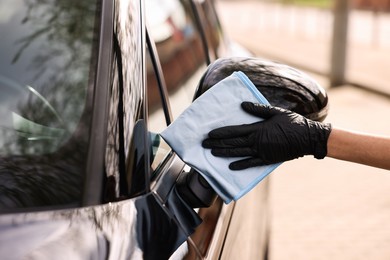 Photo of Woman wiping her modern car with rag, closeup