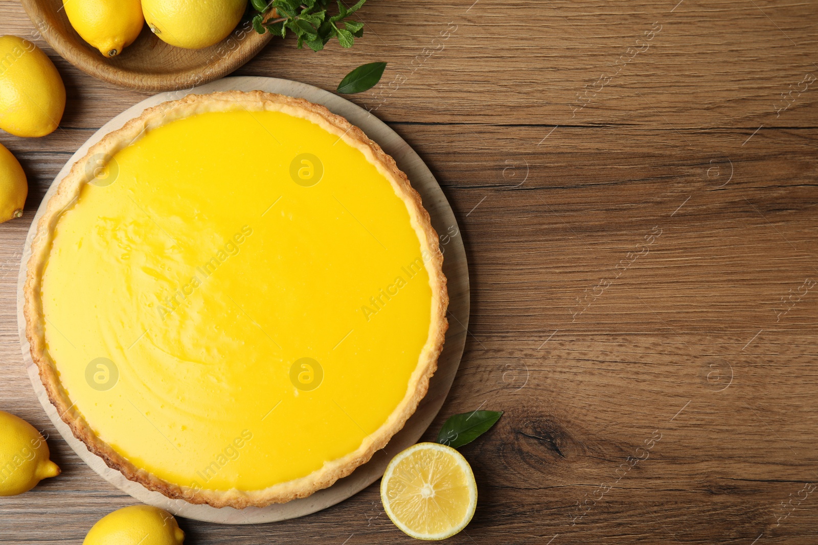 Photo of Delicious homemade lemon pie and fresh fruits on wooden table, flat lay. Space for text