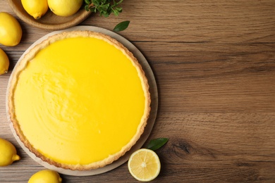 Photo of Delicious homemade lemon pie and fresh fruits on wooden table, flat lay. Space for text
