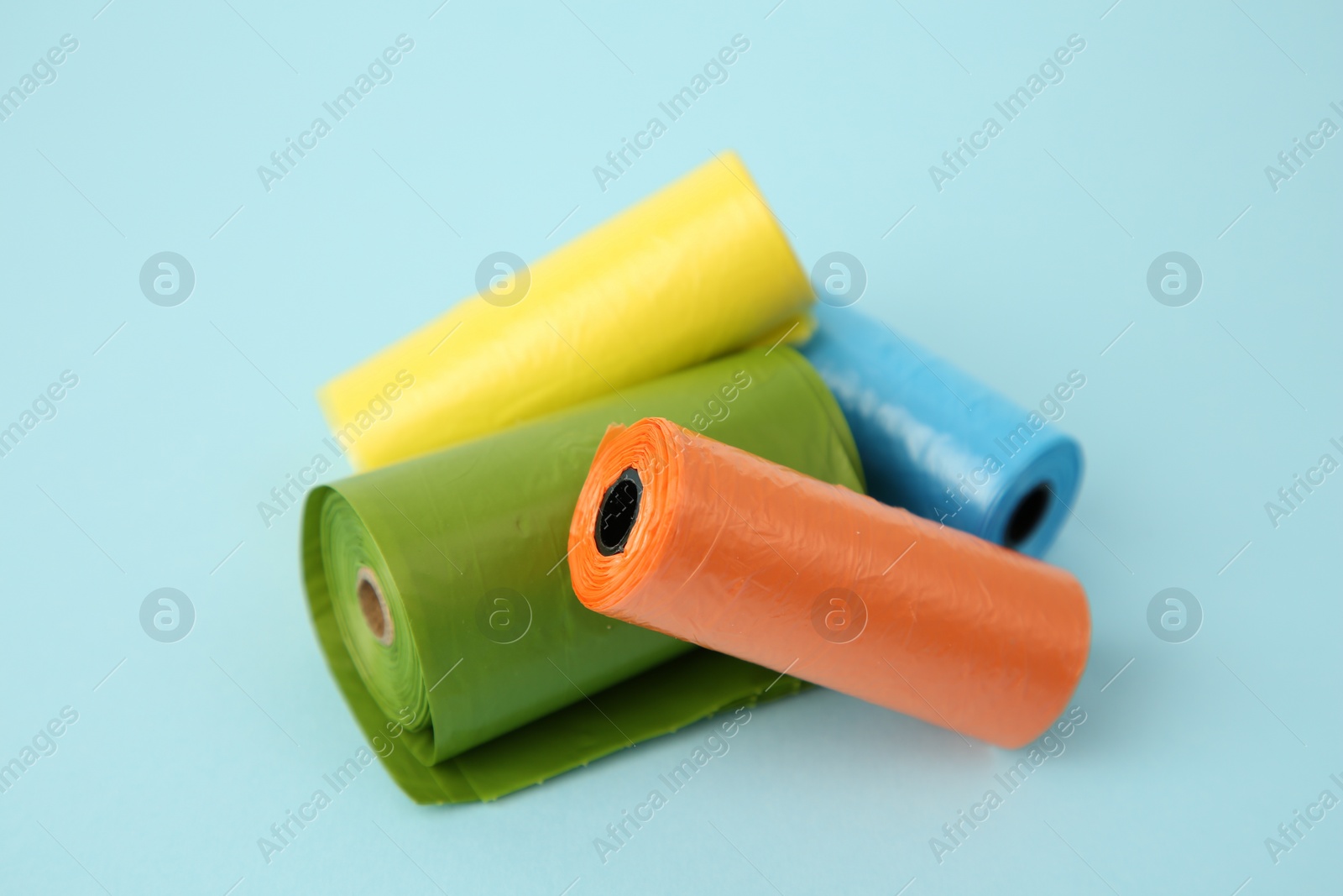 Photo of Dog waste bags on light blue background, closeup