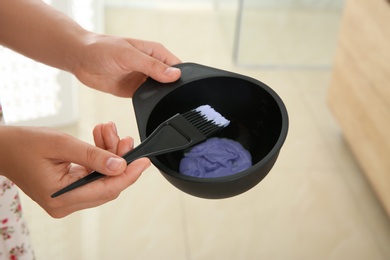 Woman preparing hair dye in bowl at home, closeup