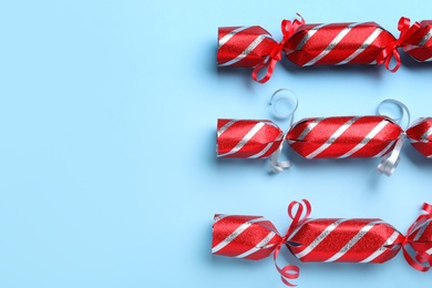 Photo of Red Christmas crackers on light blue background, flat lay. Space for text