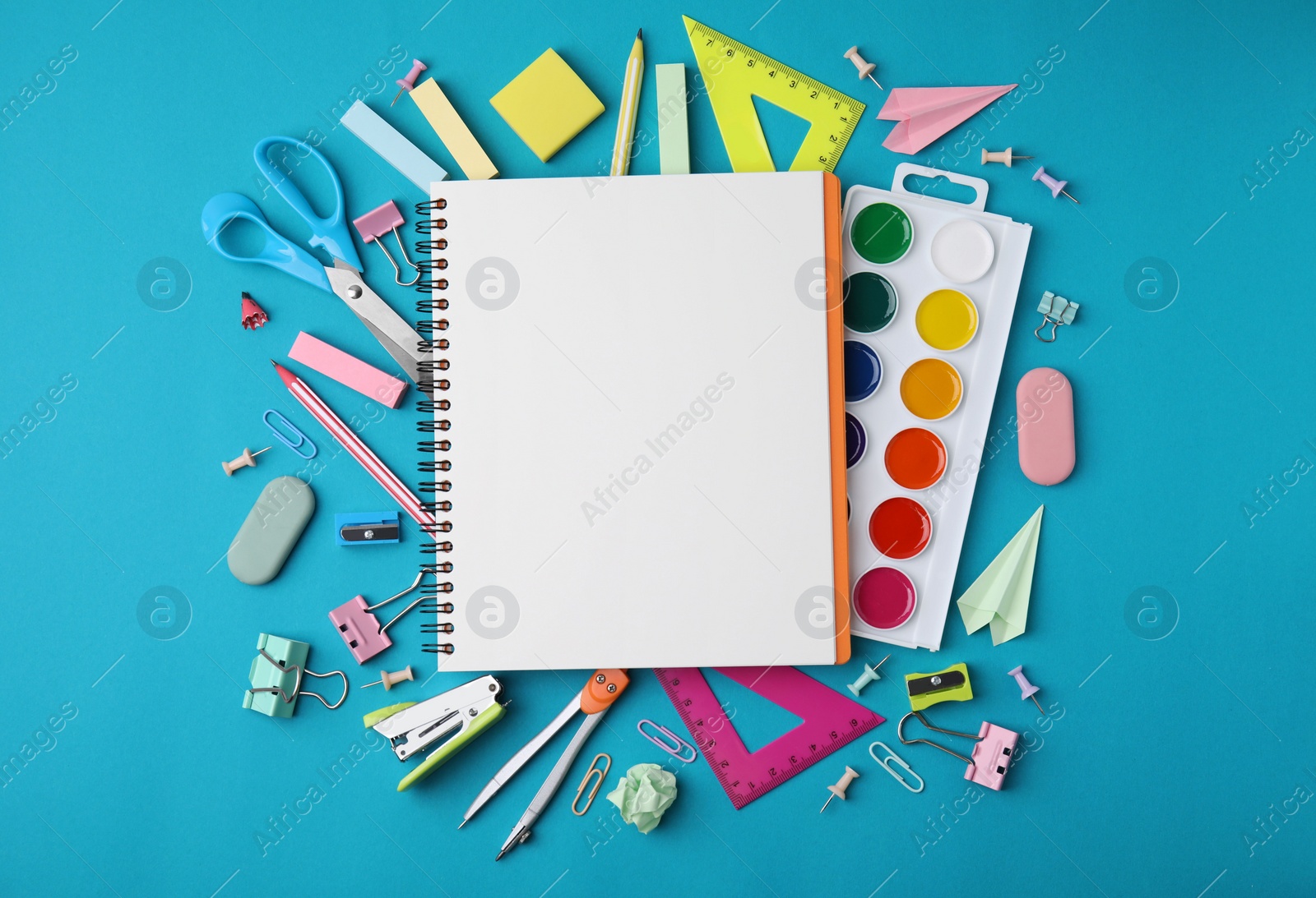 Photo of Different school stationery items and notebook on light blue background, flat lay with space for text. Back to school