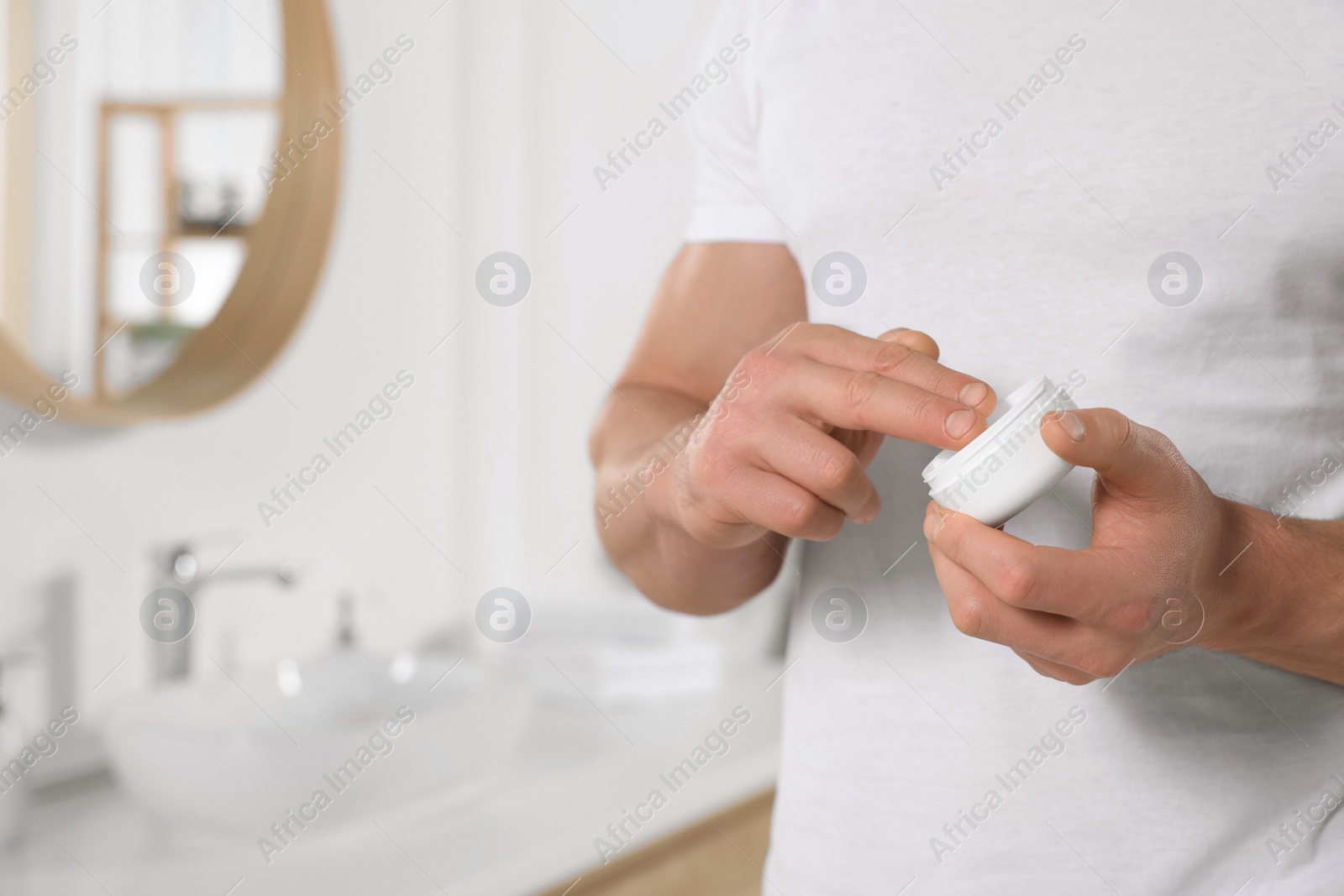 Photo of Man applying body cream in bathroom, closeup. Space for text