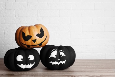 Pumpkins with scary faces near brick wall, space for text. Halloween decor