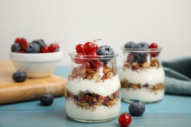 Photo of Delicious yogurt parfait with fresh berries on turquoise wooden table