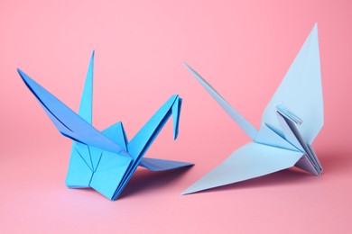 Origami art. Handmade paper cranes on pink background, closeup