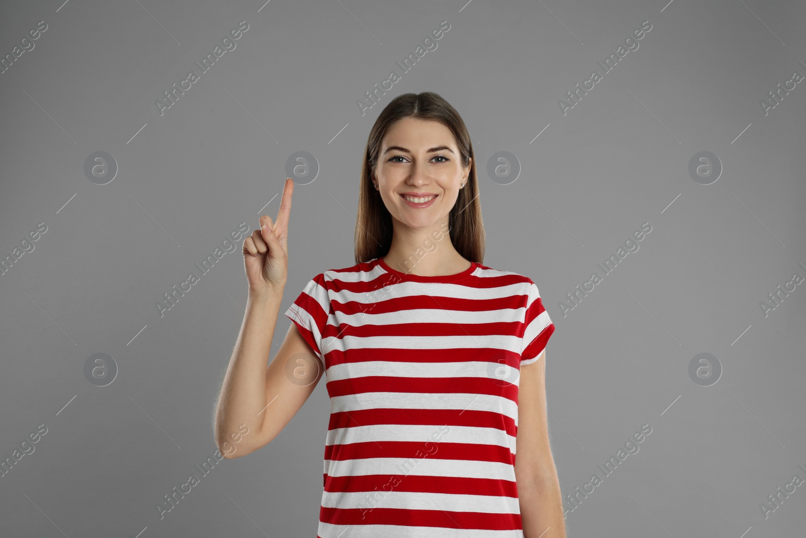 Photo of Woman showing number one with her hand on grey background