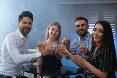 Photo of Young people toasting with Mexican Tequila shots at table in bar