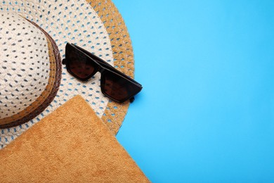 Photo of Towel, straw hat and sunglasses on light blue background, flat lay and space for text. Beach accessories
