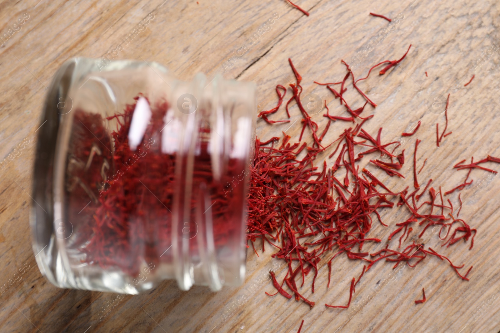 Photo of Aromatic saffron in glass jar on wooden table, top view