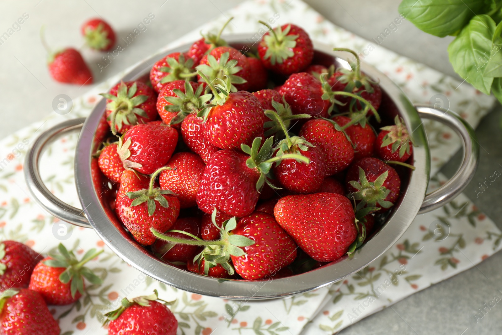 Photo of Metal colander with fresh strawberries on grey table