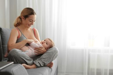 Photo of Young woman breastfeeding her baby at home. Space for text