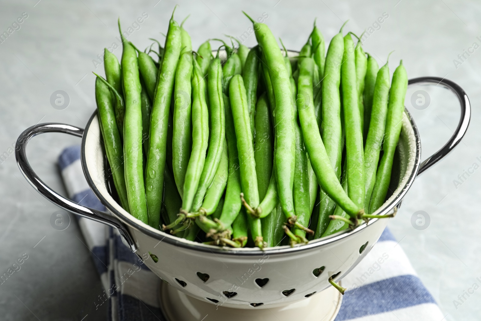 Photo of Fresh green beans in colander on light table, closeup