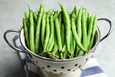 Photo of Fresh green beans in colander on light table, closeup