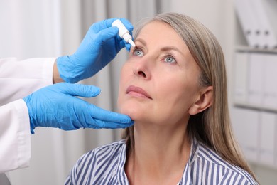 Photo of Medical drops. Doctor dripping medication into woman's eye indoors