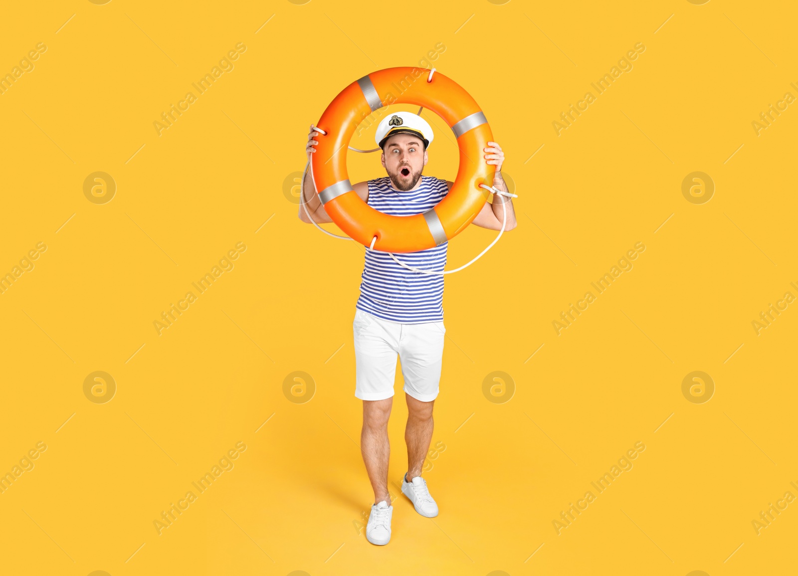 Photo of Emotional sailor with ring buoy on yellow background