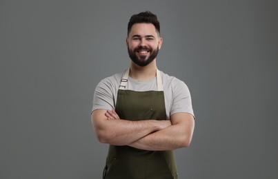 Smiling man in kitchen apron with crossed arms on grey background. Mockup for design