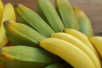 Bunches of tasty bananas on wooden table, closeup