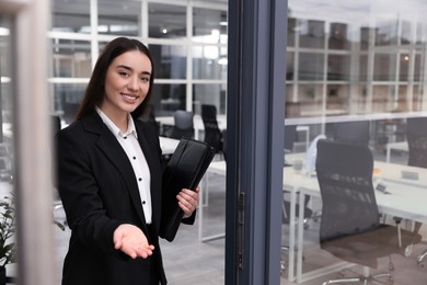 Female real estate agent with leather portfolio inviting inside