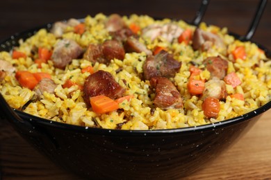 Photo of Delicious pilaf with meat and carrot on wooden table, closeup