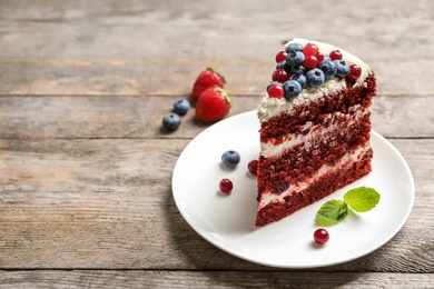 Plate with piece of delicious homemade red velvet cake and space for text on wooden table