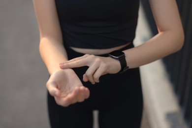 Photo of Woman checking pulse after training outdoors, closeup