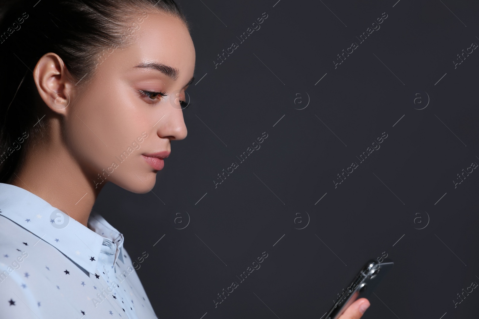 Photo of Young woman unlocking smartphone with facial scanner on black background. Biometric verification