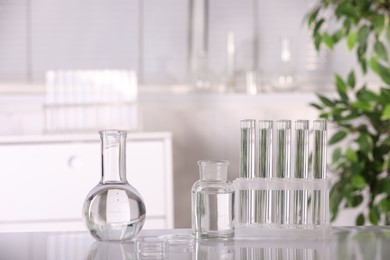 Photo of Laboratory analysis. Different glassware with liquid on white table indoors