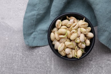 Sprouted kidney beans in bowl on light grey table, top view. Space for text