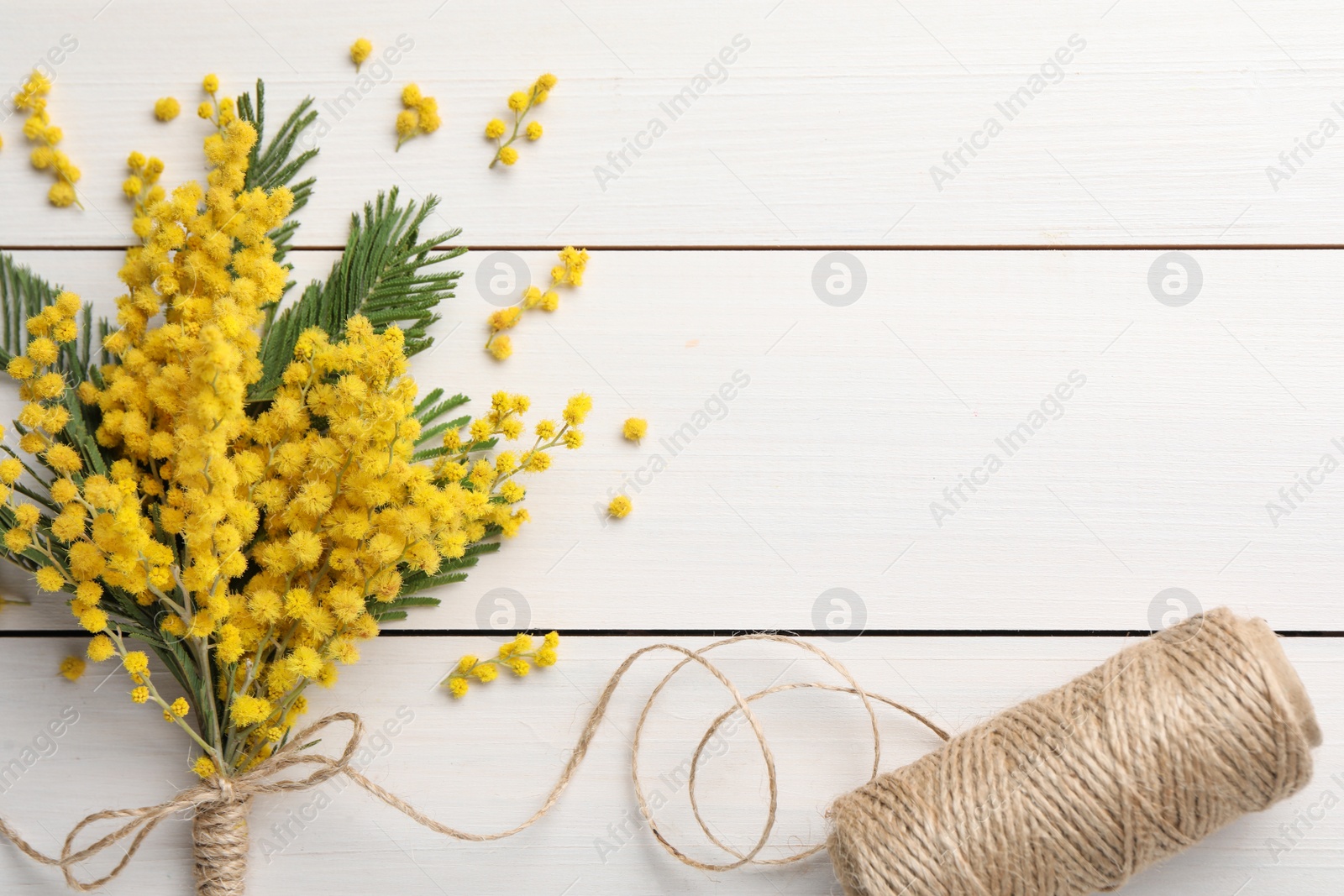 Photo of Beautiful mimosa flowers and twine on white wooden table, flat lay. Space for text