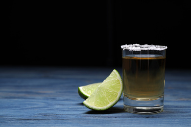 Photo of Mexican Tequila shot with salt and lime on blue wooden table. Space for text