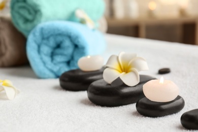 Candles, flower and stones on massage table in spa salon, closeup