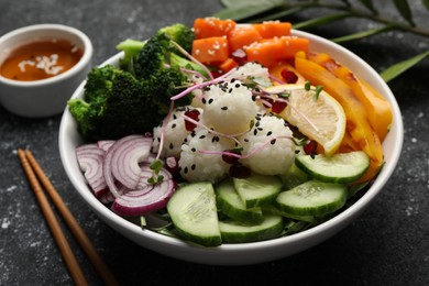 Photo of Bowl with many different vegetables and rice on grey textured table. Vegan diet