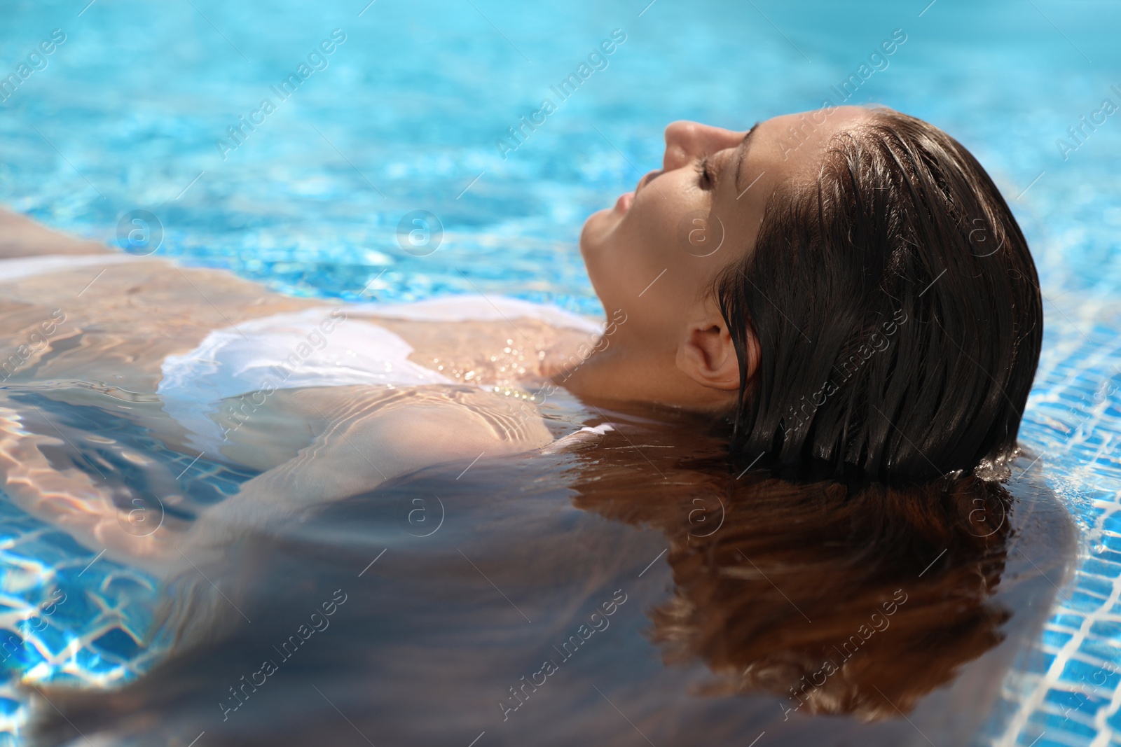 Photo of Beautiful young woman relaxing in outdoor swimming pool